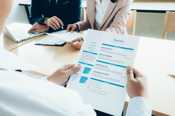 A person holding a document during a meeting with two others at a table.