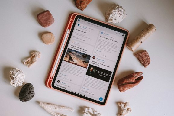 An iPad displaying social media content, surrounded by various stones and shells.